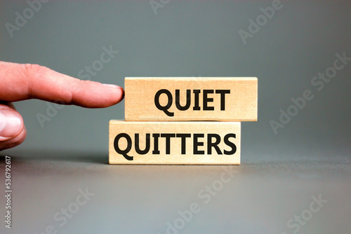 Quiet quitters symbol. Concept words Quiet quitters on wooden blocks. Beautiful grey table grey background. Businessman hand. Business and quiet quitters concept. Copy space. photo