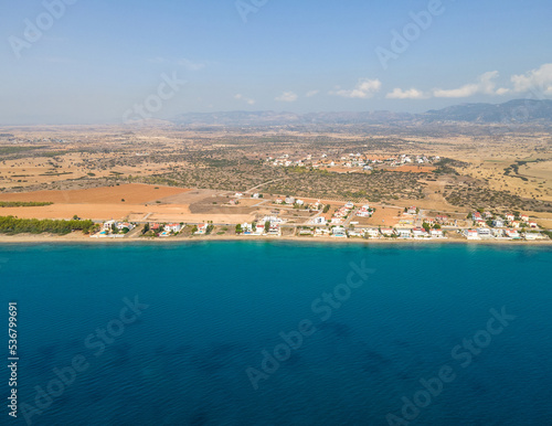 View from the sea. Seascape of the surface of the Mediterranean Sea with beautiful villas on the coast. Drone view. Exotic island of Cyprus.