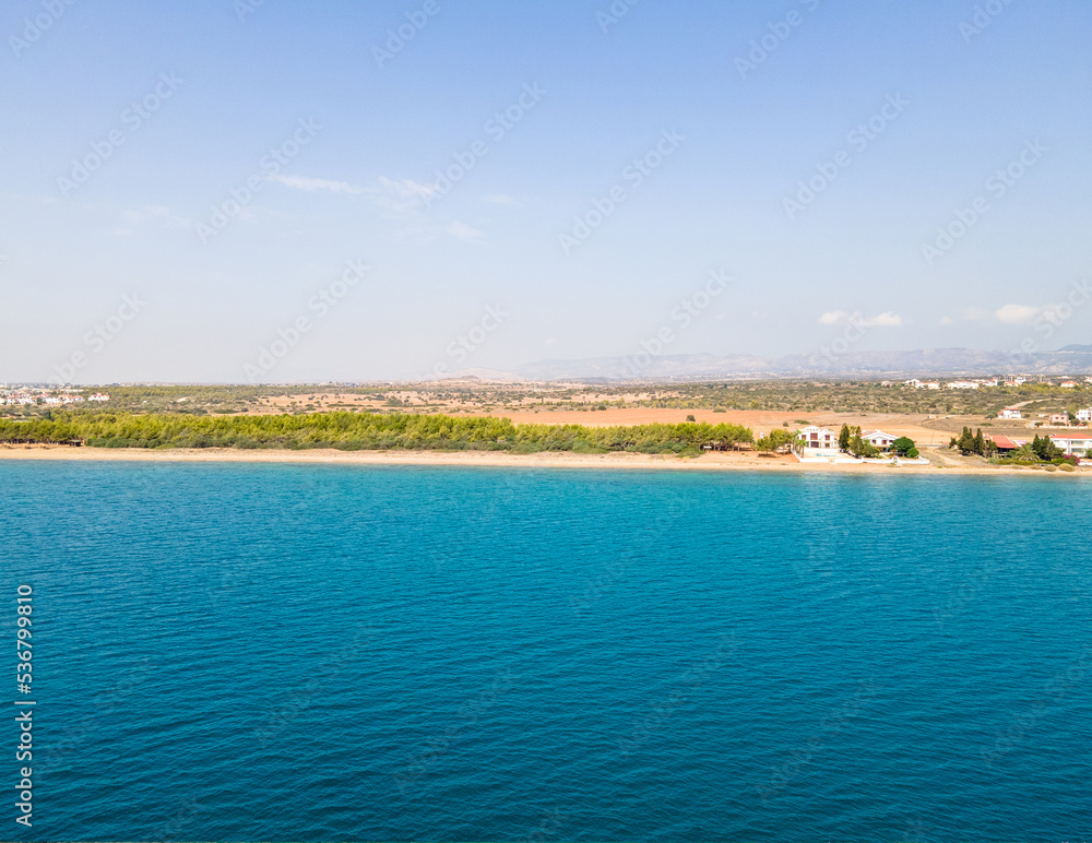 View from the sea. Seascape of the surface of the Mediterranean Sea with beautiful villas on the coast. Drone view. Exotic island of Cyprus.