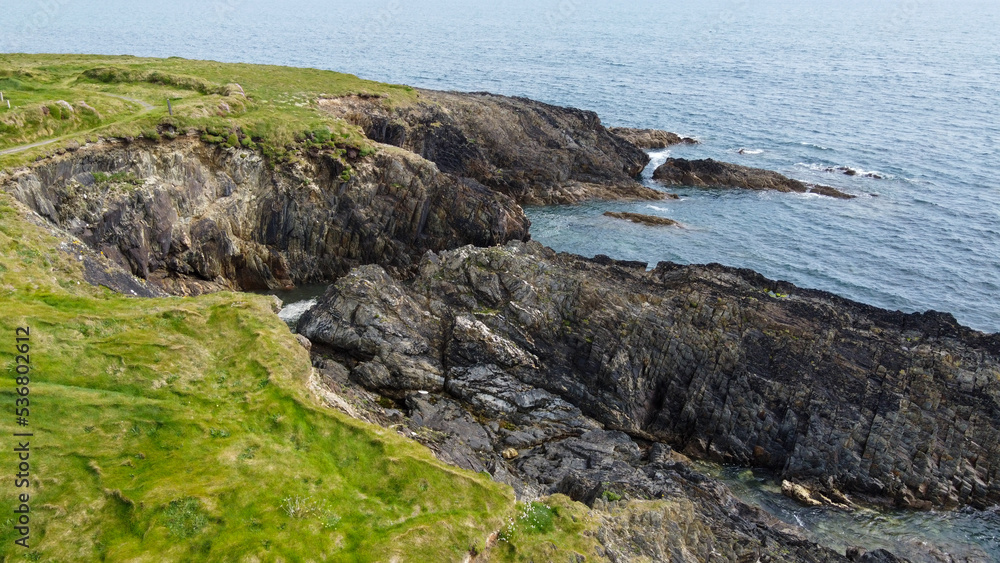 Drone point of view. Beautiful Irish coast of the Atlantic Ocean, top view. Nature of Northern Europe. Coastal rocks covered with green grass. Aerial photo.