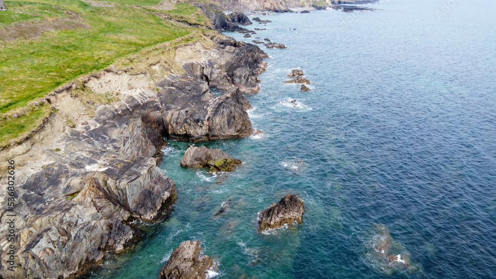 Beautiful sea water near steep coastal cliffs. The nature of Ireland. Dangerous reefs and cliffs of northern Europe.