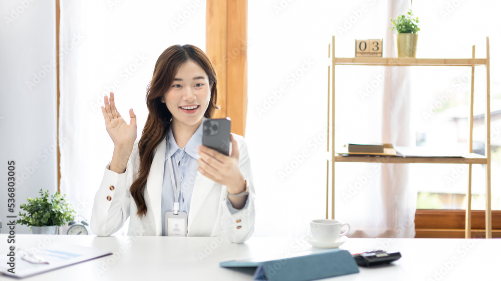 Finance workers are reviewing the company's financial data on a laptop and using smartphones to communicate or chat with the team during social distances, Talk on the phone or video call. Finance workers are reviewing the company's financial data on a laptop and using smartphones to communicate or chat with the team during social distances, Talk on the phone or video call.