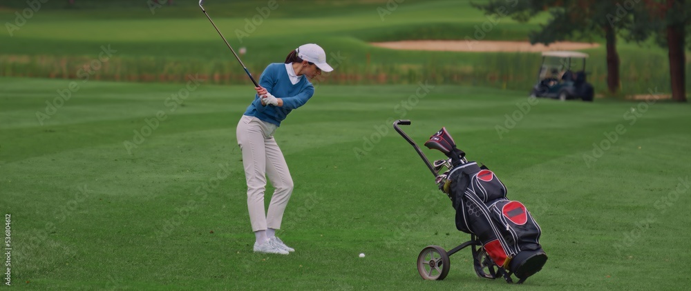 Caucasian female playing golf, striking a ball during the course Caucasian female playing golf, striking a ball during the course