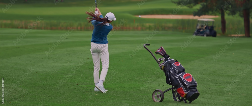 Caucasian female playing golf, striking a ball during the course Caucasian female playing golf, striking a ball during the course