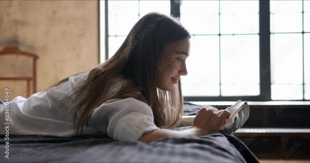 Girl with bionic arm using phone, reading social media and chatting in bed, woman with disability learning or working online remotely from home Girl with bionic arm using phone, reading social media and chatting in bed, woman with disability learning or working online remotely from home