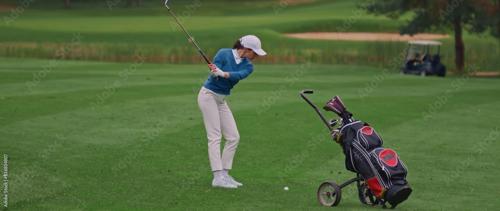 Caucasian female playing golf, striking a ball during the course Caucasian female playing golf, striking a ball during the course