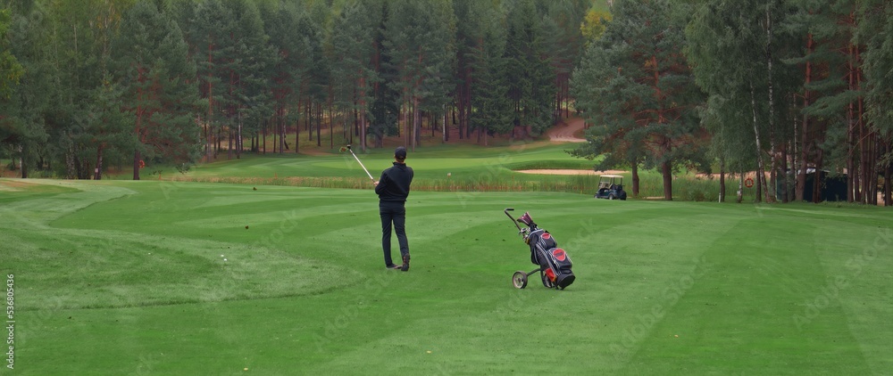 Caucasian man playing golf, striking a ball during the course Caucasian man playing golf, striking a ball during the course