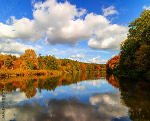Autumn landscape forest and lake with cloudy sky reflection.