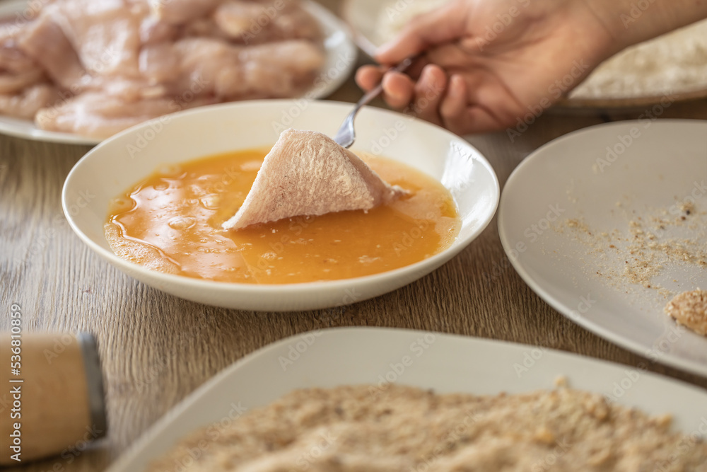 Detail of hand putting chicken meat in flour into eggs during making schnitzels Detail of hand putting chicken meat in flour into eggs during making schnitzels