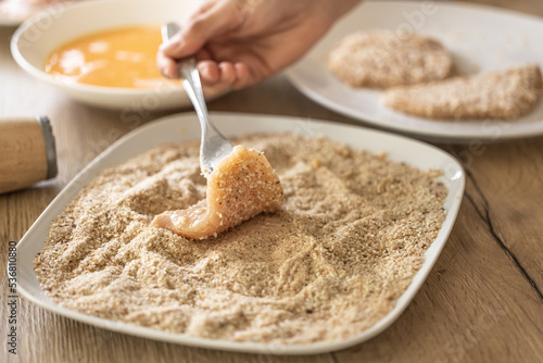 Final stage of coating meat in breadcrumbs while making schnitzels