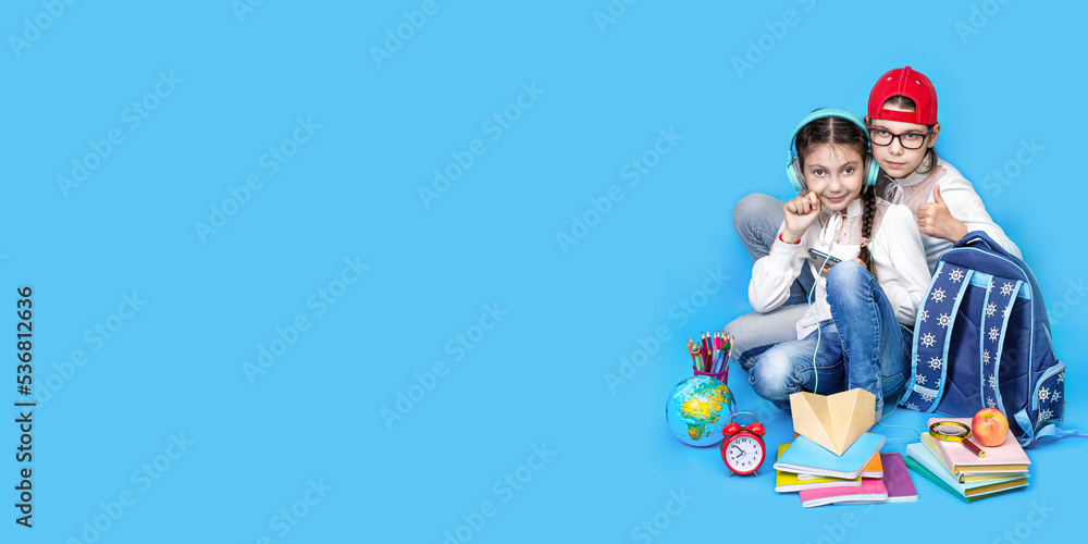 Obraz premium Back to school. Portrait of school girl, Girls sisters in glasses sit floor on blue background