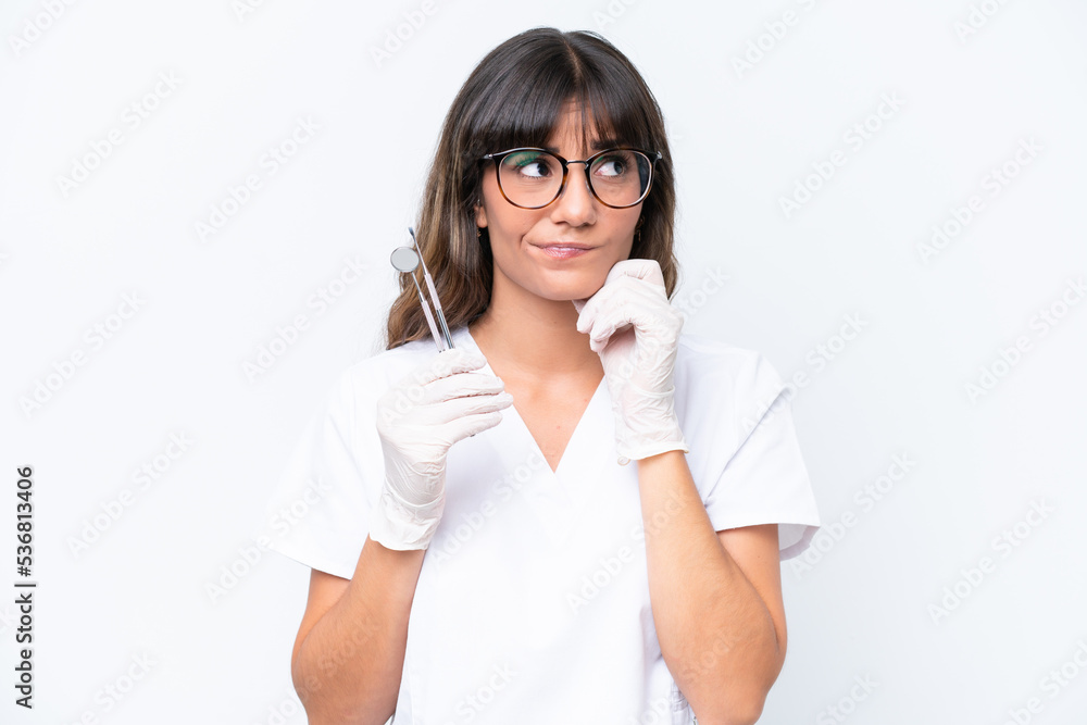 Dentist caucasian woman holding tools isolated on white background having doubts and thinking Dentist caucasian woman holding tools isolated on white background having doubts and thinking