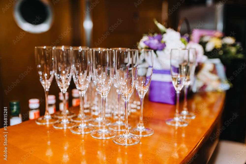 A lot, a row of empty transparent wine glasses stands on a wooden table in a bar, cafe. A lot, a row of empty transparent wine glasses stands on a wooden table in a bar, cafe.