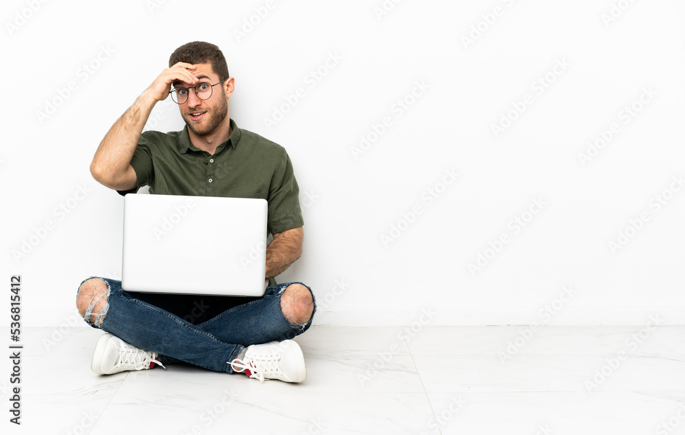 Young man sitting on the floor doing surprise gesture while looking front Young man sitting on the floor doing surprise gesture while looking front