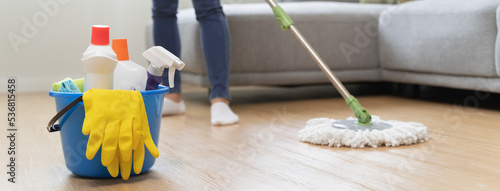 happy Female housekeeper service worker mopping living room floor by mop and cleaner product to clean dust.