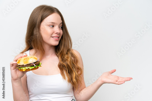 Young pretty woman holding a burger isolated on white background with surprise facial expression