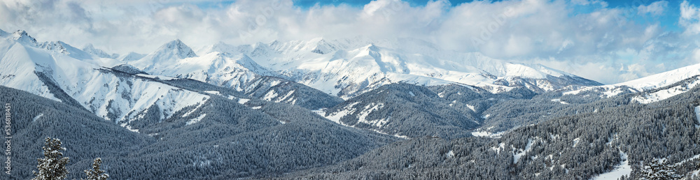 Panorama of the snow covered peaks in the clouds