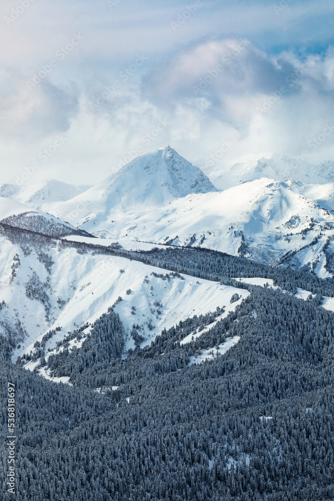 Snow covered mountain peaks in the clouds
