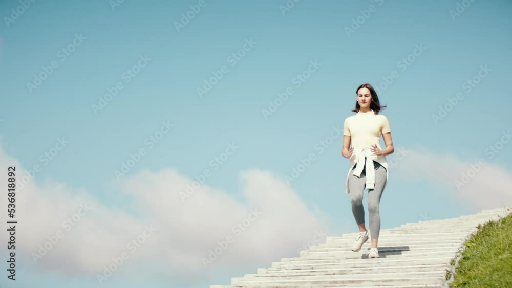 Fitness young adult woman running on stairs. Female workout on sky background. Amazing view stairs to haven. Active sports person jogging and reaching the aim. Fitness young adult woman running on stairs. Female workout on sky background. Amazing view stairs to haven. Active sports person jogging and reaching the aim.