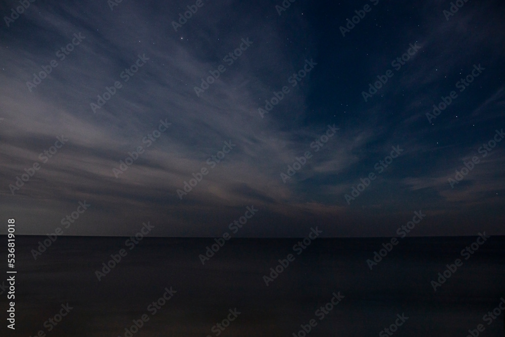 Starry sky with clouds and sea in the evening in autumn