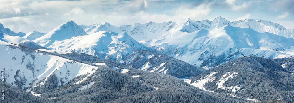 Panorama of the snow covered peaks in the clouds