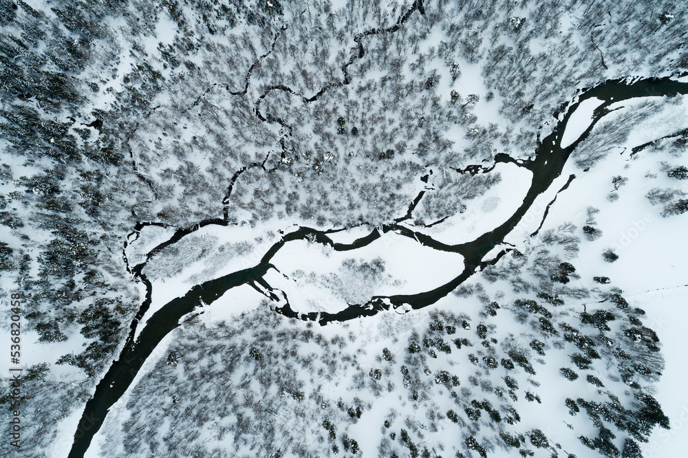 Top view of a mountain river running through a winter forest