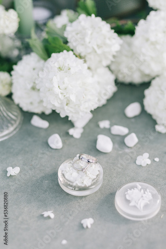 Wedding rings on a table with white flowers and a jewelry box. Wedding day details.