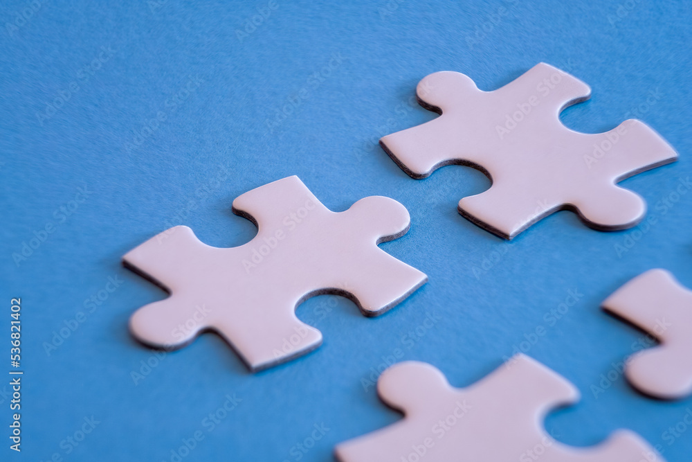 White jigsaw puzzle pieces on blue background with limited close up focus. White jigsaw puzzle pieces on blue background with limited close up focus.