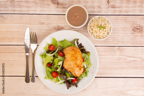 Healthy salad with chicken on a plate, lettuce, organic vegetables, rice and beans, top view