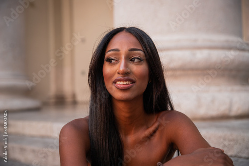 Fotografía Portrait of an attractive, smiling young African girl sitting on the steps in to