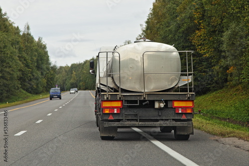 Milk barrel truck drive on countryside road . Liquid food goods delivery