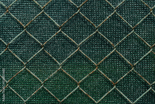 Metal grid on green background. Pattern. Protective fence against thieves, home railing with farbic, Selective focus photo