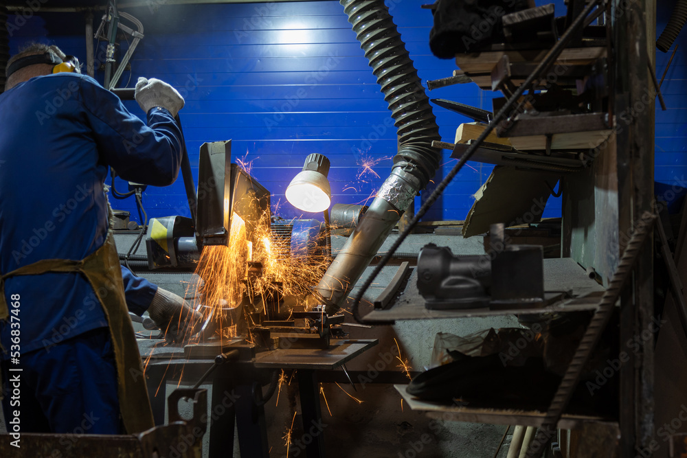 Workplace in metallurgical production. Processing of cast metal products with a grinding disc.