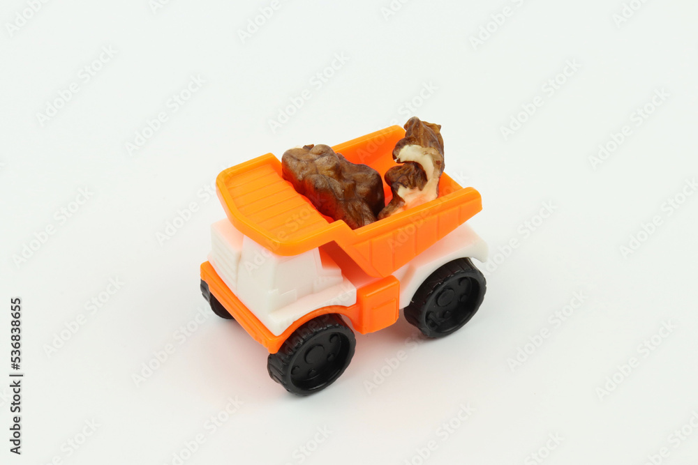 Naklejka premium Walnut pieces in a small orange toy truck bed, white background