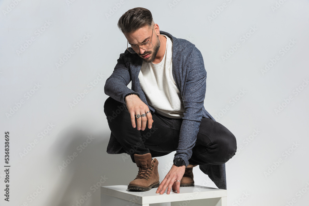 © Viorel Sima - casual man with eyeglasses looking down while holding elbow on knee © Viorel Sima - casual man with eyeglasses looking down while holding elbow on knee