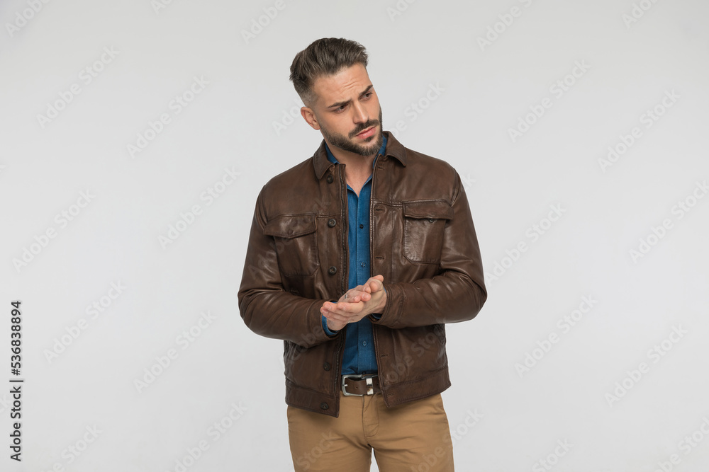 handsome man wearing brown leather, looking to side and rubbing palms handsome man wearing brown leather, looking to side and rubbing palms