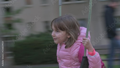 Cute little girl is spinning on a carousel and waving emotionally