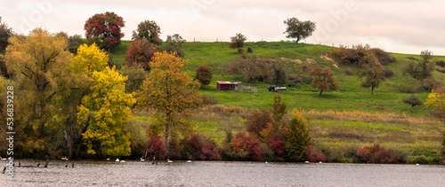 Landschaft im Herbst mit Himmel, Wiesen, Bäumen, Schuppen, Wasser