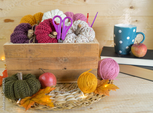 colorful crochet woolen pumkins in wooden box with lights, woolen balls and a mug with hot cofeee in a cozy atmosphere photo