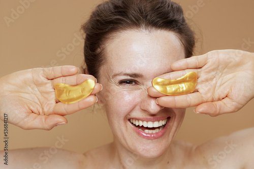 Tela happy young woman with eye patches against beige background