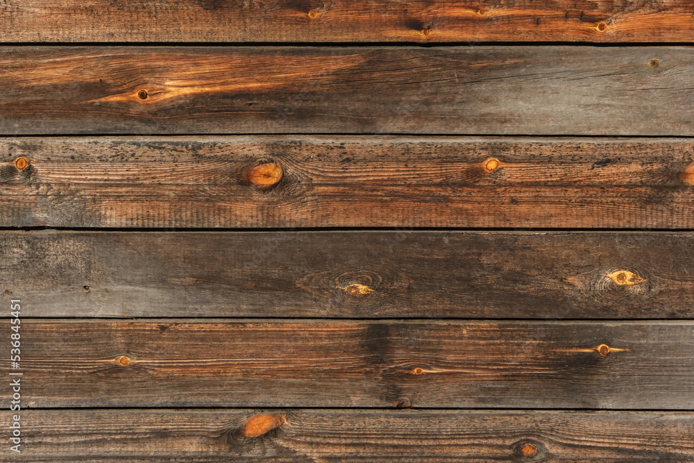 Fototapeta premium Wooden texture with horizontal lines. The texture of wood with knots and holes. The background of a wooden fence damaged by time. The texture of a tree with moss.