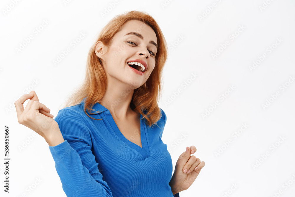 Close up portrait of dancing happy woman, singing and rejoicing, posing against white background in blue blouse Close up portrait of dancing happy woman, singing and rejoicing, posing against white background in blue blouse
