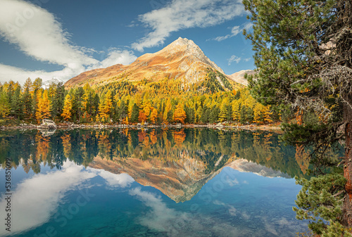 autumn view of Saoseo lake in the Dolomites. Fantasy autumn scene with colorful sky  majestic rocky mountain and colorful trees glowing with sunlight