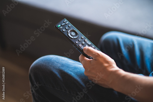 Man spending time at home and swithcing on tve with a tv remote photo