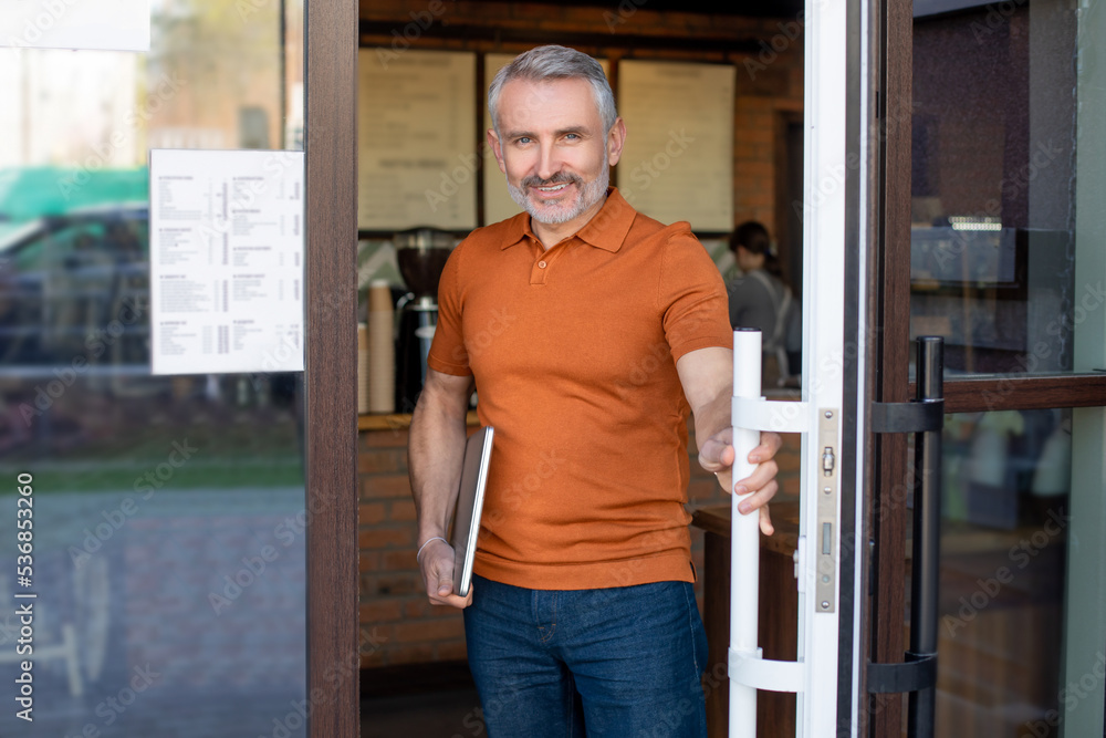 Fototapeta premium Mature confident man with notebook at the cafe entrance