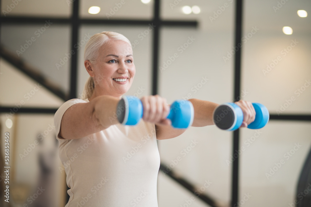 Joyful woman working out with hand weights Joyful woman working out with hand weights