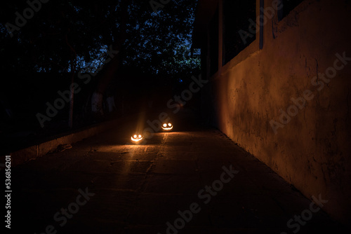 Pumpkin Burning In Forest At Night - Halloween Background. Scary Jack o Lantern smiling and glowing pumpkin with dark toned foggy background. Selective focus