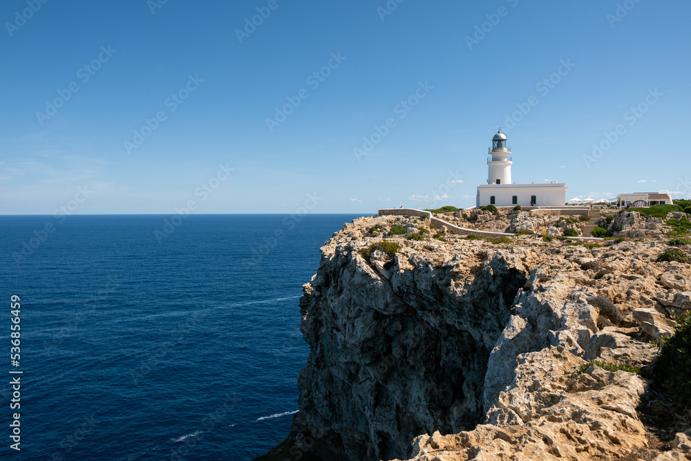 Faro de Cavalleria con mar azul en calma y cielo despejado en isla de menorca