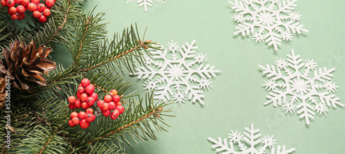 Snowflakes, fir branches and berries on green background, closeup