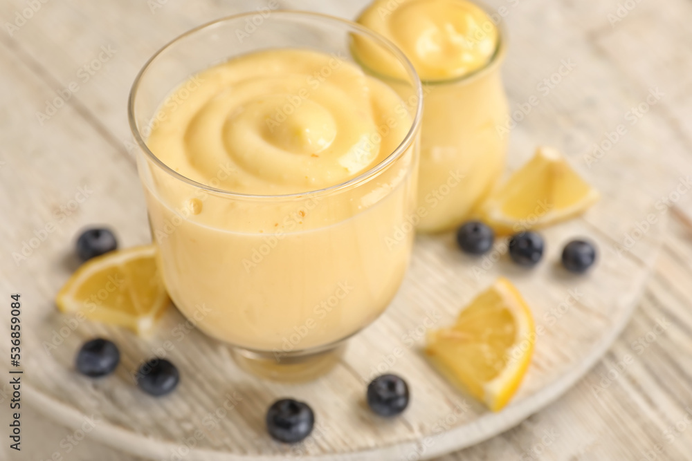 Glass bowl of tasty vanilla pudding on light wooden table, closeup Glass bowl of tasty vanilla pudding on light wooden table, closeup